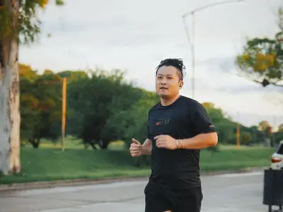 A man jogs outdoors in casual sportswear.