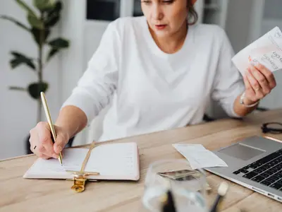 A woman writes in a notepad at her desk.